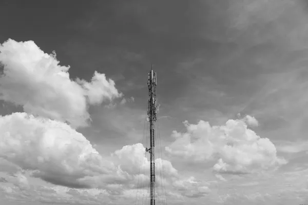 Traliccio di un’antenna per telecomunicazioni contro un cielo nuvoloso, in bianco e nero