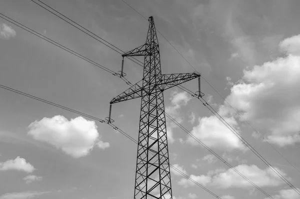 Traliccio dell’alta tensione visto dal basso contro un cielo azzurro con nuvole