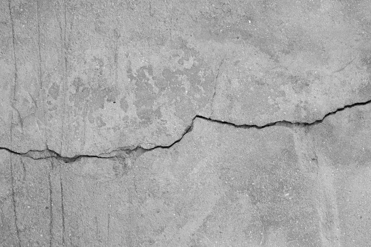 Fessura che attraversa una superficie in calcestruzzo dilavato, dettaglio ravvicinato, fotografia in bianco e nero
