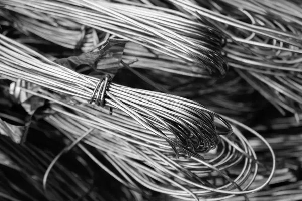 Bundles of bare, stripped copper wire, coiled and piled on top of each other, black-and-white photograph