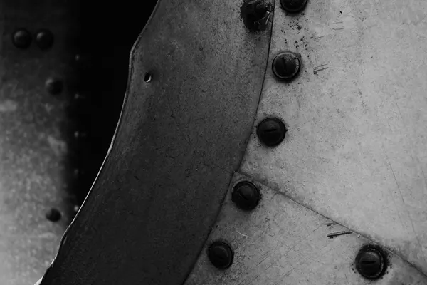 Rusted screws along the overlap of two galvanised metal sheets, with one hole left empty