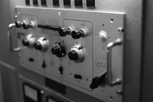 A vintage instrument panel with control knobs and a graduated scale, in black and white