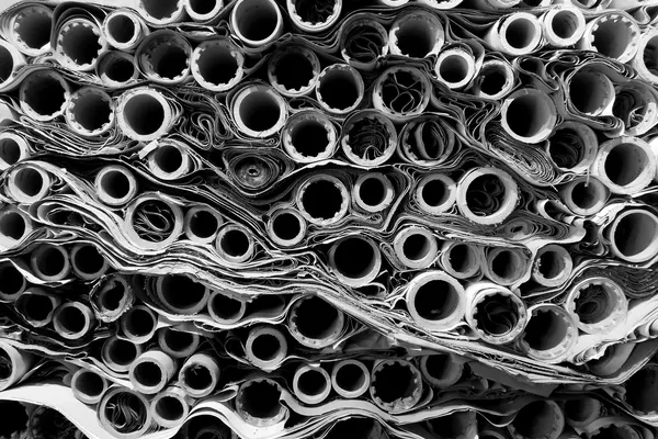 Parete compatta di disegni tecnici arrotolati, visti di testa, decine di cilindri di carta accatastati l’uno sull’altro, fotografia in bianco e nero