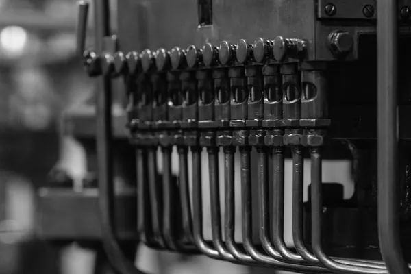 Copper earthing bus bar with several conductors clamped in place, black and white photograph on a neutral grey background