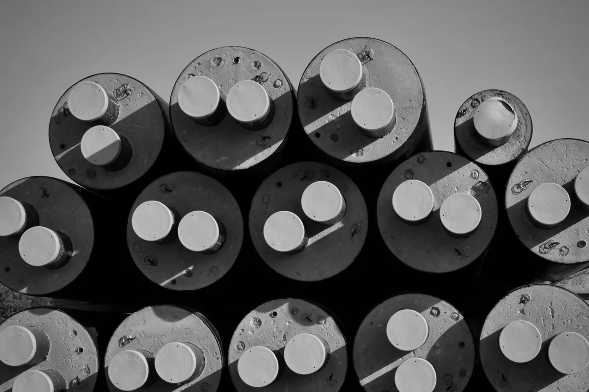 Ends of large pipes side by side, each closed by two smaller circular caps, seen from above in raking light, black and white photograph