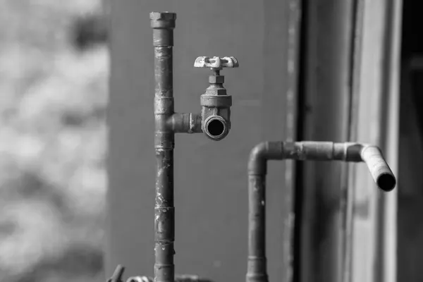 Two metal pipe stubs ending open in mid-air, with a gate valve that has no outlet fitting, black and white photograph