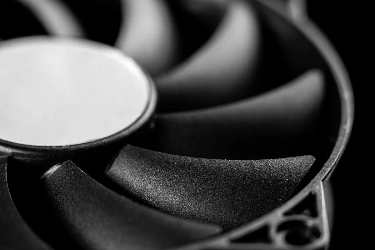 Close-up of the black blades of a cooling fan, pale central hub, black and white photograph