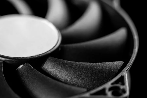 Close-up of the black blades of a cooling fan, pale central hub, black and white photograph
